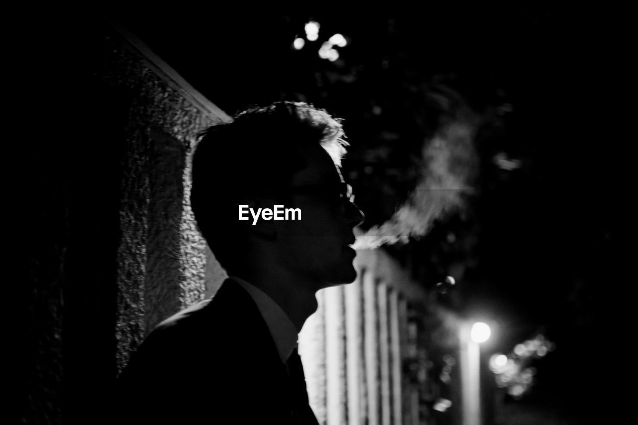 Side view of man smoking at night