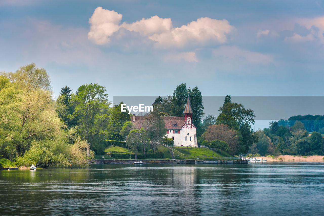 SCENIC VIEW OF LAKE BY TREES AND BUILDING AGAINST SKY