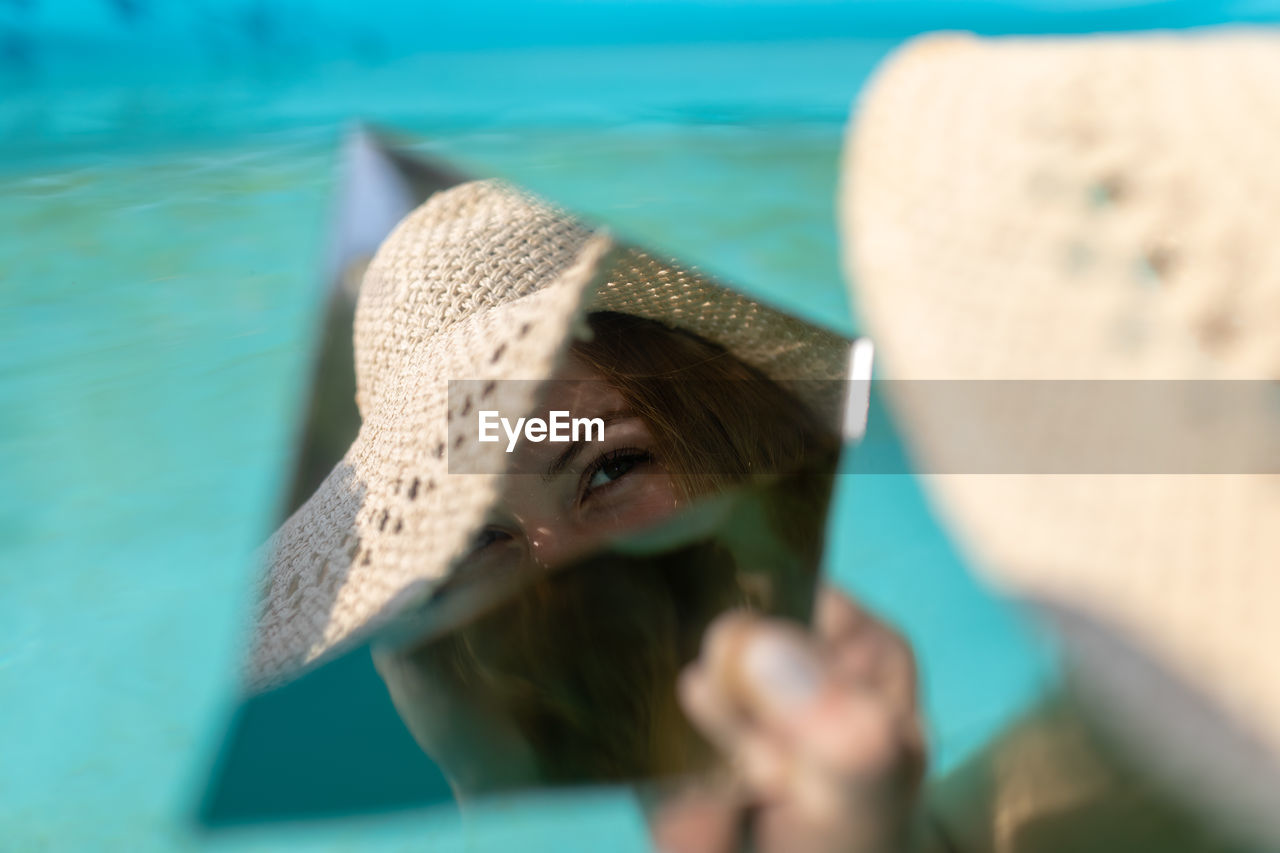 Reflection of woman in mirror while sitting in swimming pool