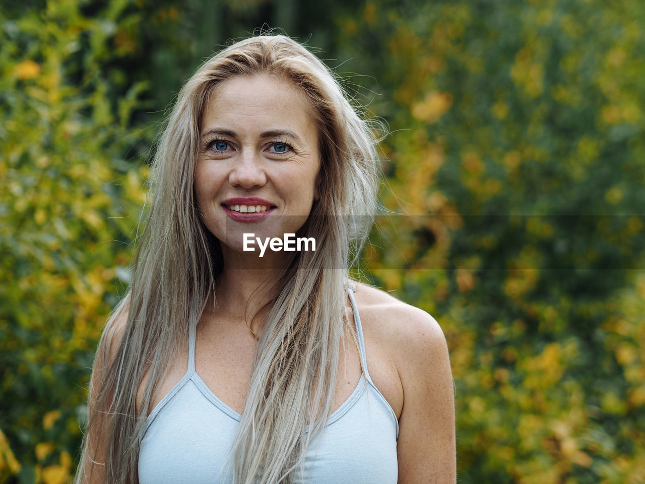 Young beautiful blond woman with long hair in activewear smiling on camera after training