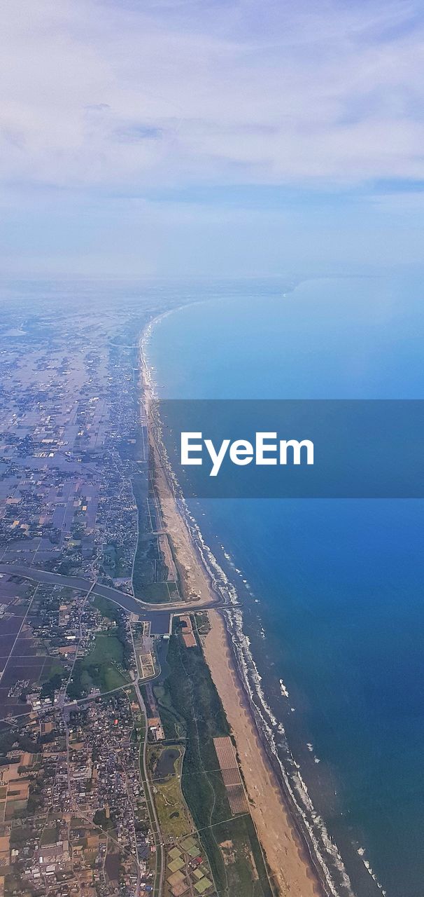 Aerial view of city by sea against sky