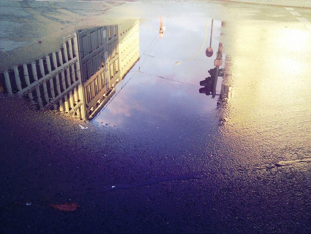 High angle view of reflection of building on puddle at street