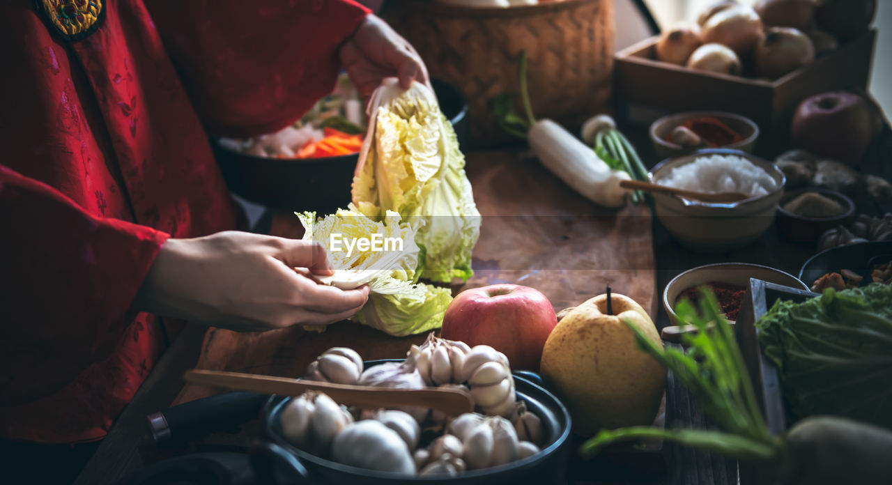 Korean woman is wearing a traditional hanbok, she making kimchi which is a fermentation food 