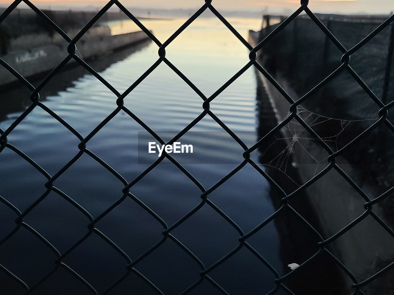 Full frame shot of chainlink fence and water channel to ocean