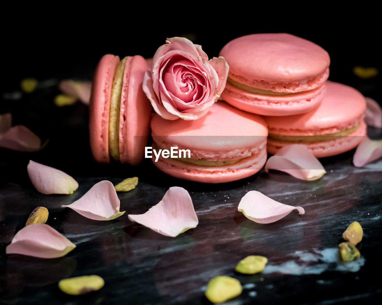 Pink pistachio rose macarons against a black background