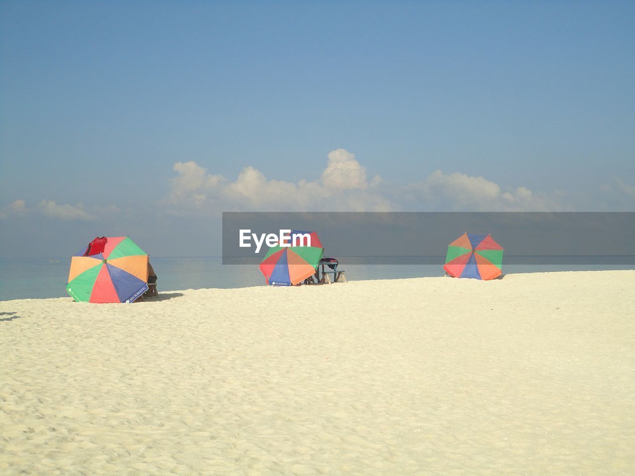 Beach umbrellas on sand against sky