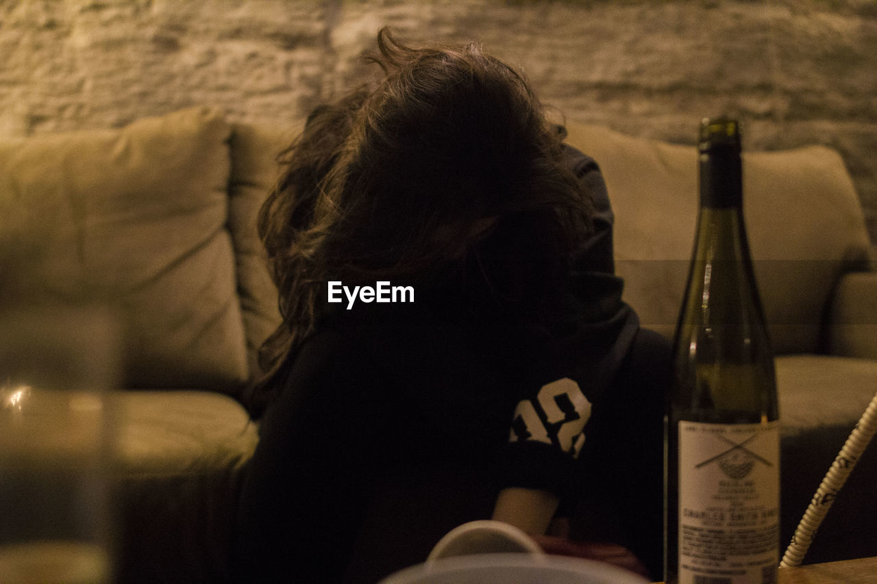 Woman with obscured face sitting on couch