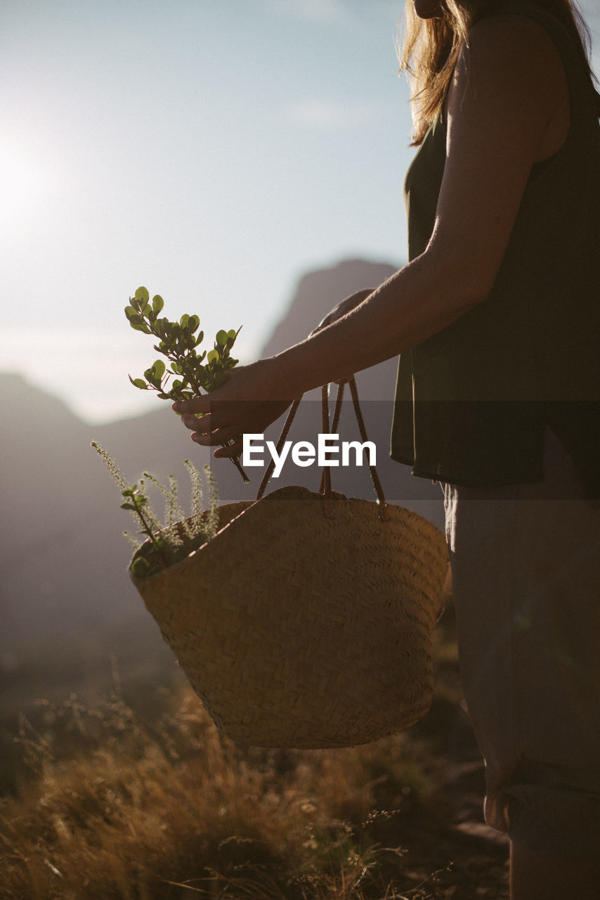 Midsection of woman with bag standing on land