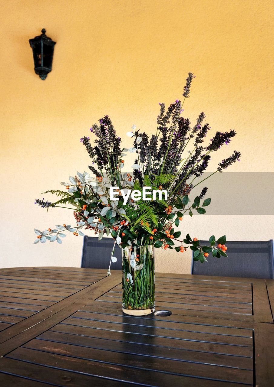 Flower vase on table against wall at home