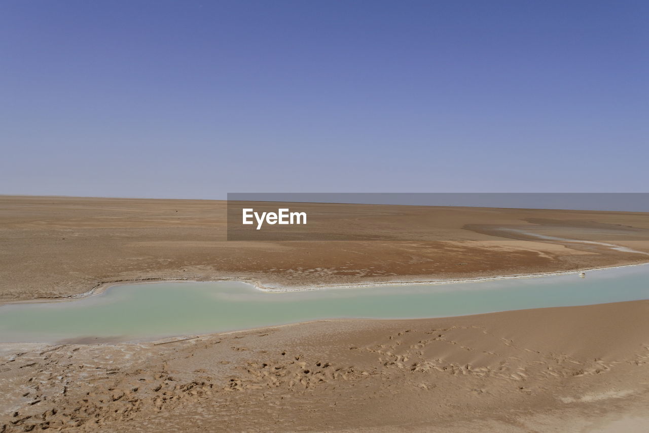 Scenic view of desert against clear blue sky