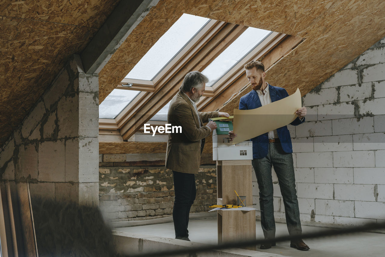 Businessman explaining blue print to colleague at construction site