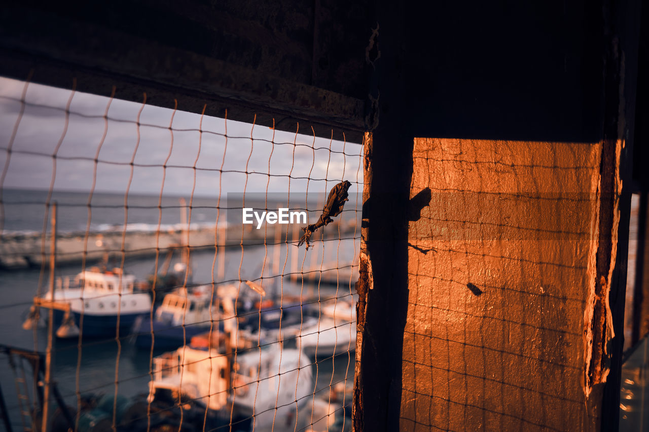 High angle view of of a sea port through a barred window with the light of the sunset 