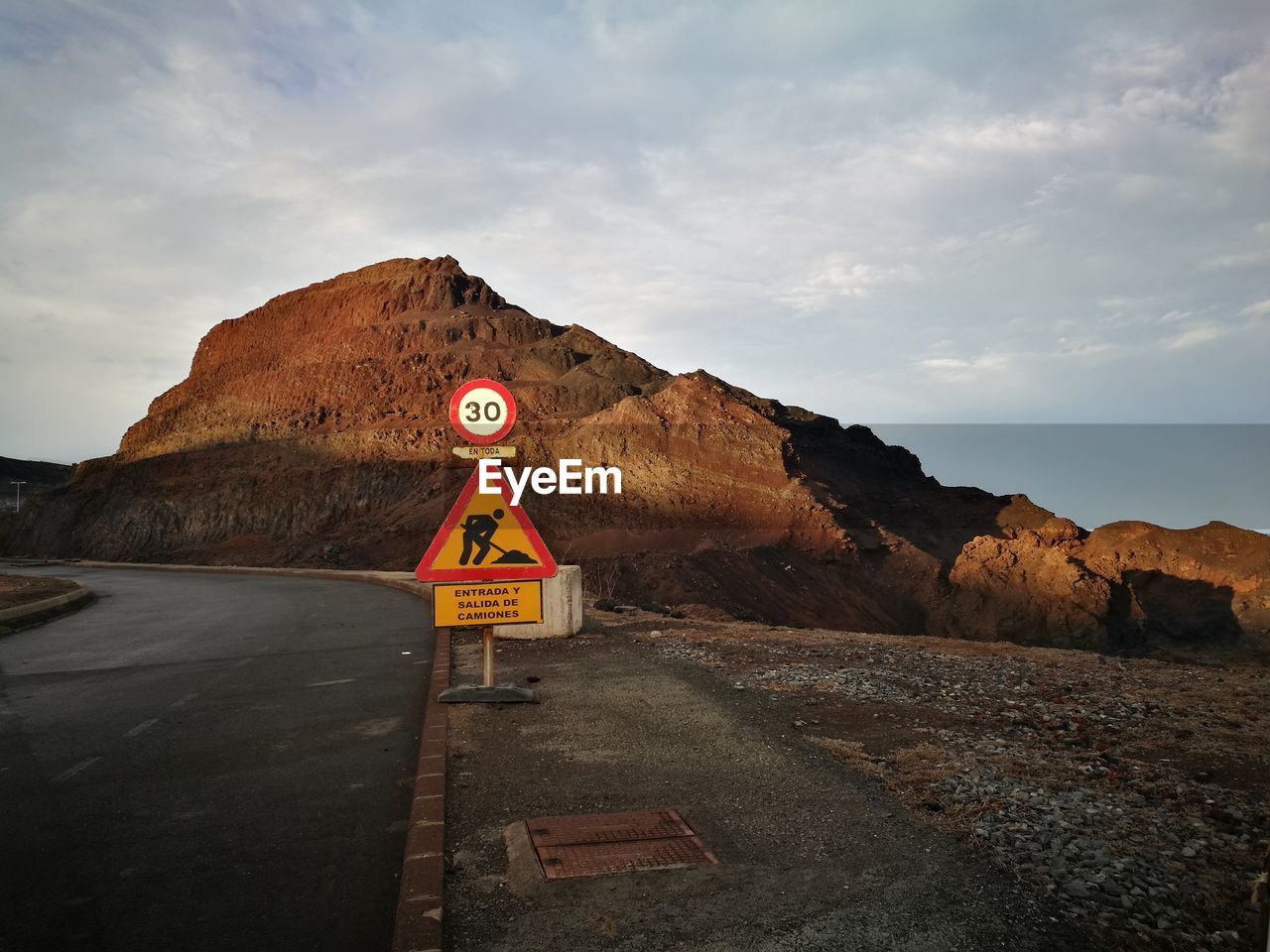 Road sign by mountains against sky