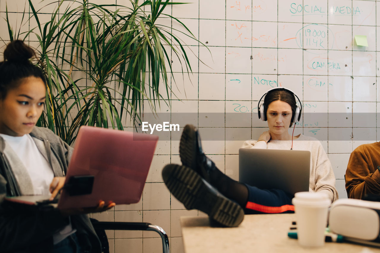 Young multi-ethnic female computer programmers using laptops at small creative office