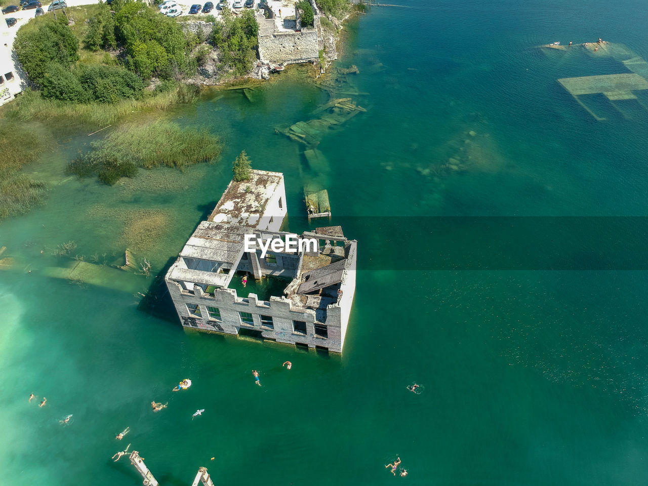 High angle view of people swimming by ruined building in sea