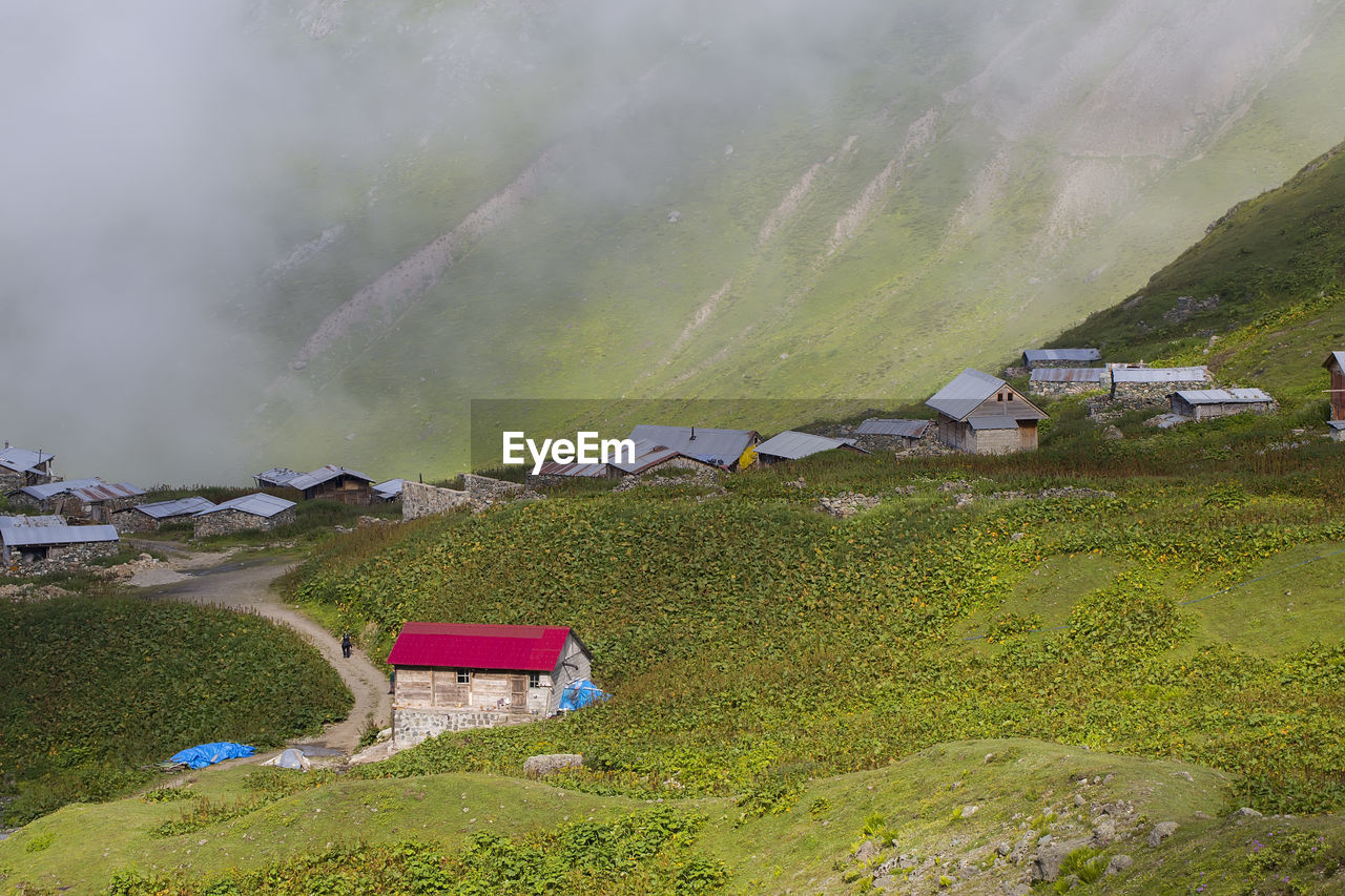 High angle view of houses by mountain during foggy weather