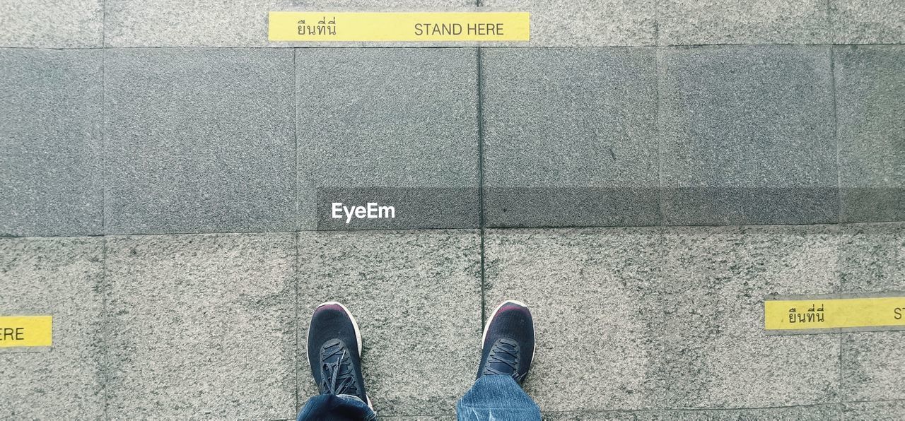 LOW SECTION OF PERSON STANDING ON ROAD SIGN