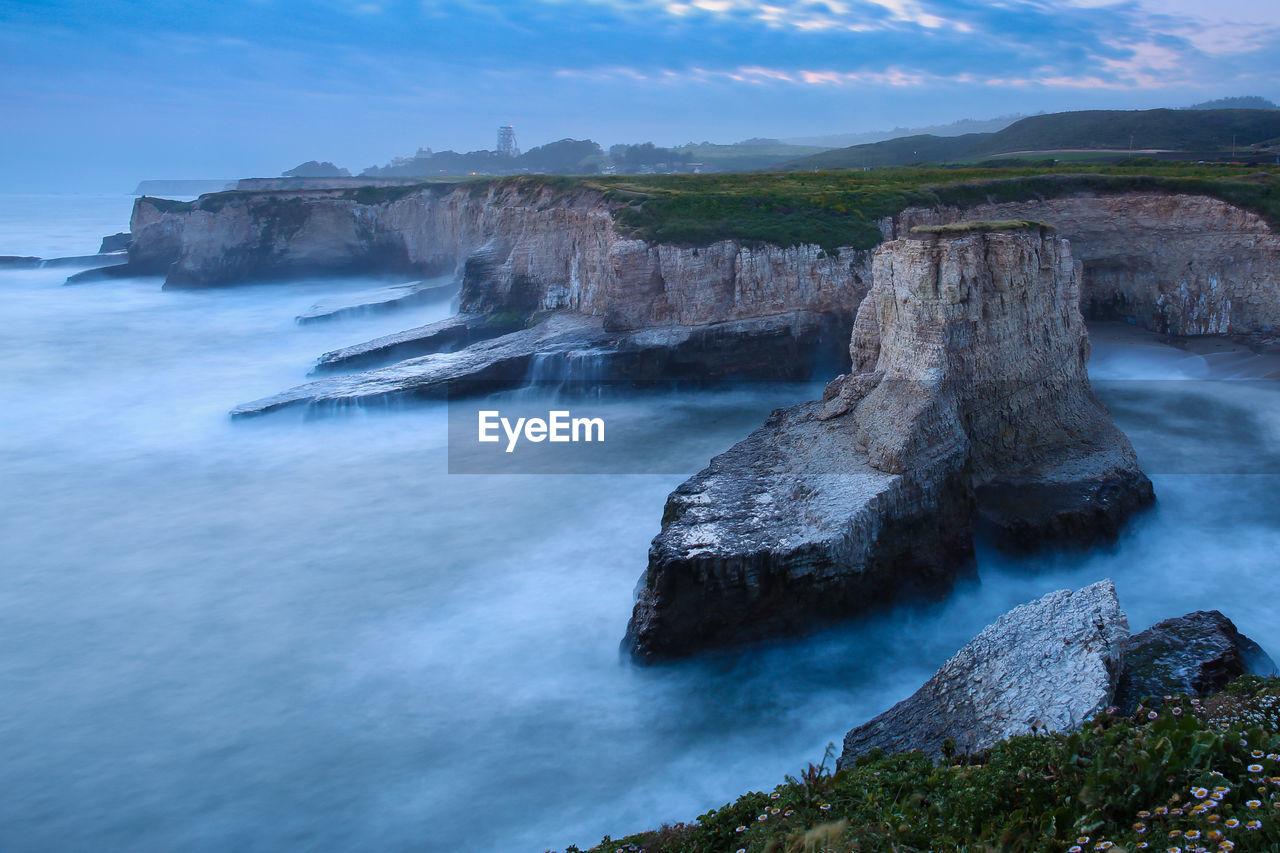 Scenic view of cliffs by sea at shark fin cove beach
