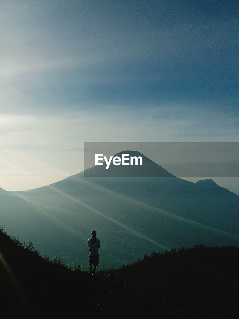 Man standing on the hill staring at the mountain 