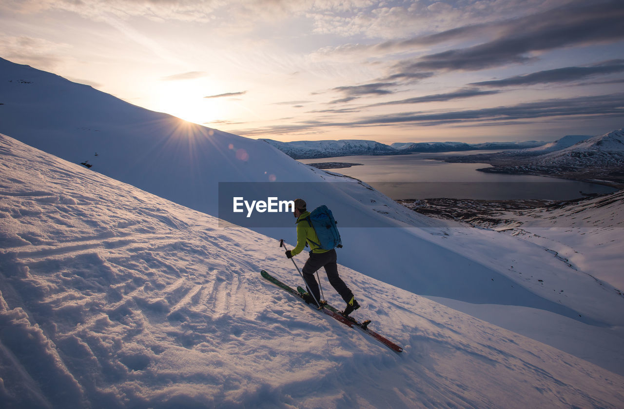 Man skiing in iceland at sunrise with water behind him