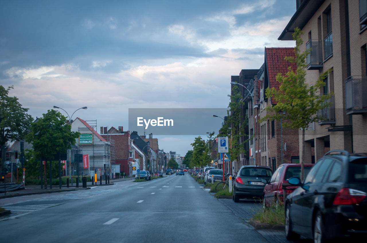 STREET AMIDST BUILDINGS IN CITY AGAINST SKY