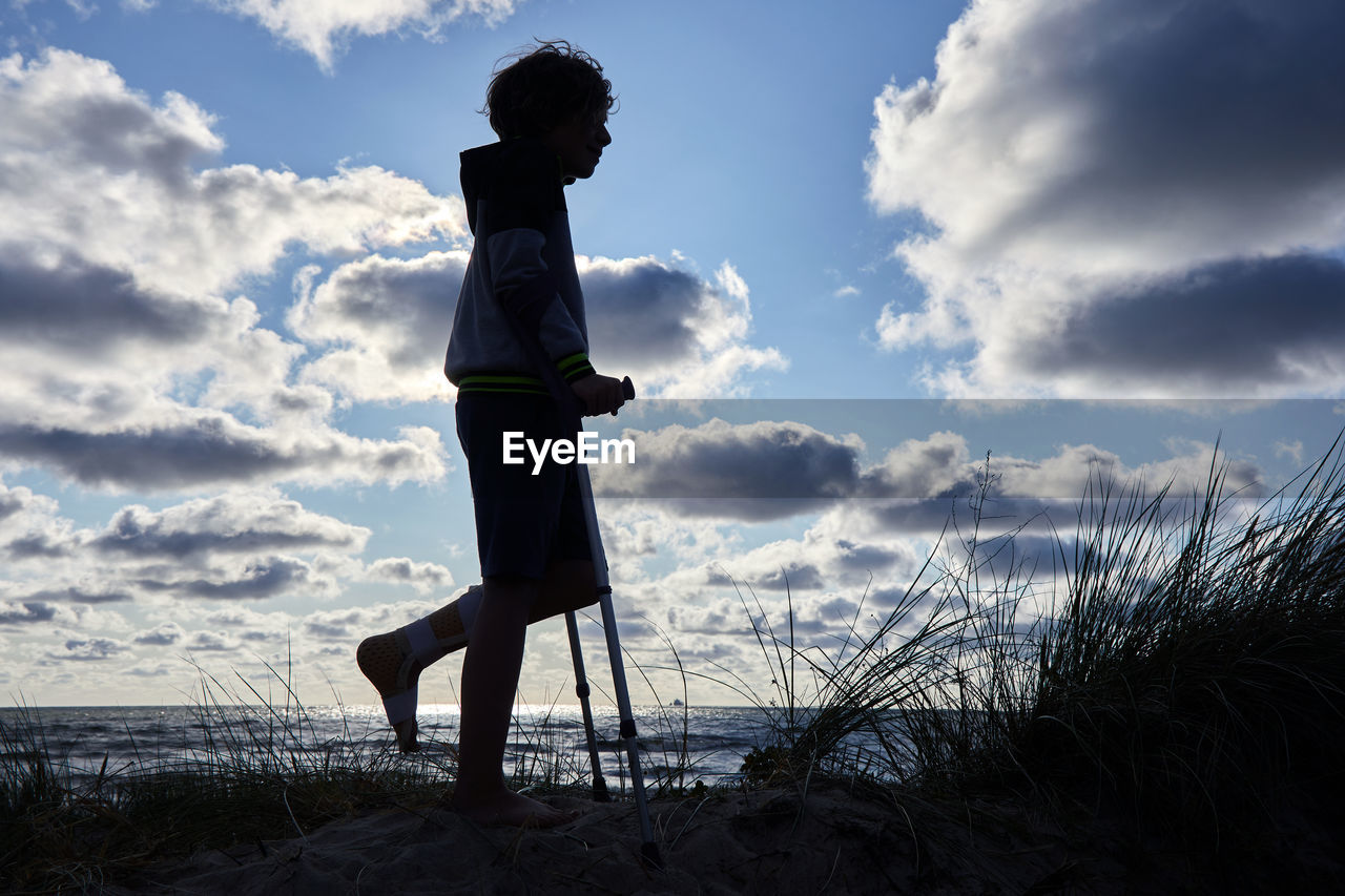 SIDE VIEW OF WOMAN STANDING AT BEACH