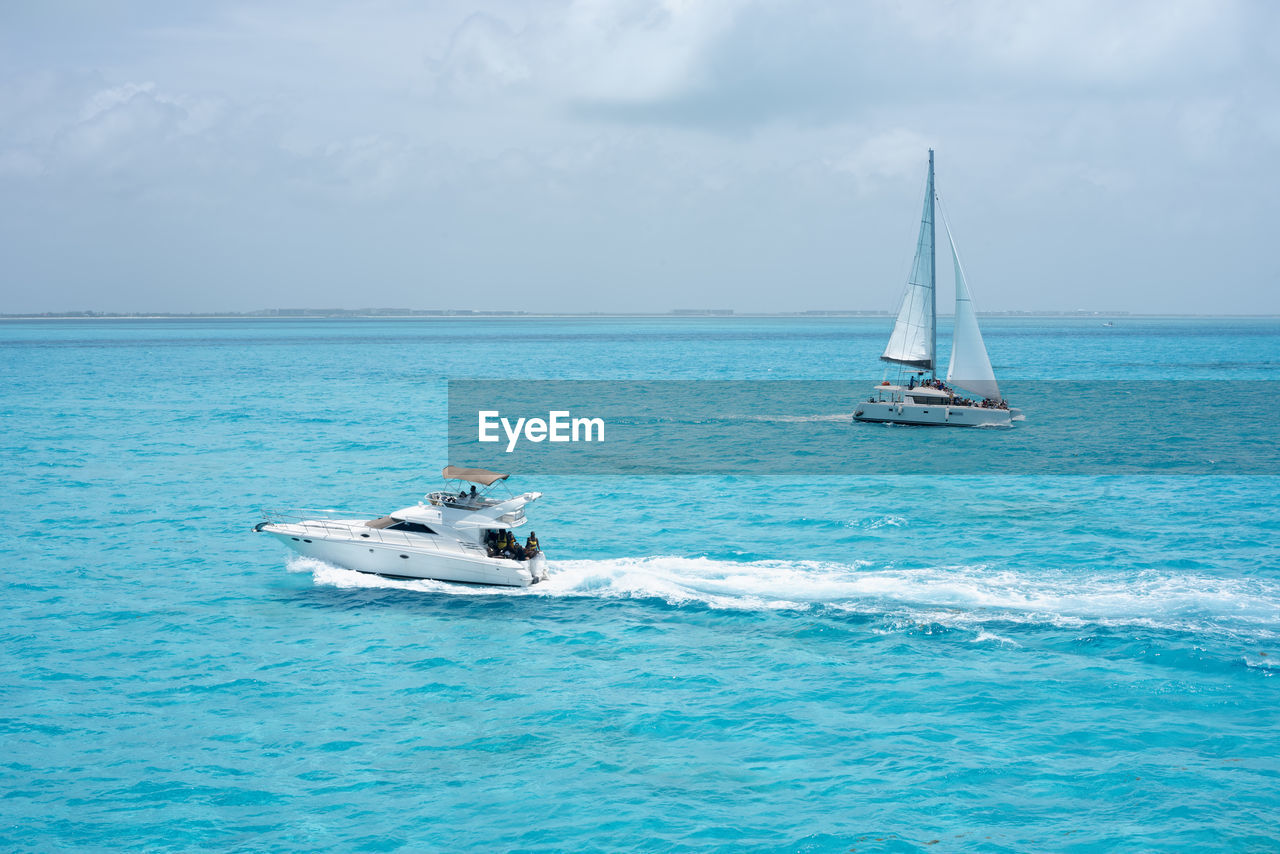 Luxury yacht and catamaran sail the turquoise mexican caribbean sea near the coast of isla mujeres.