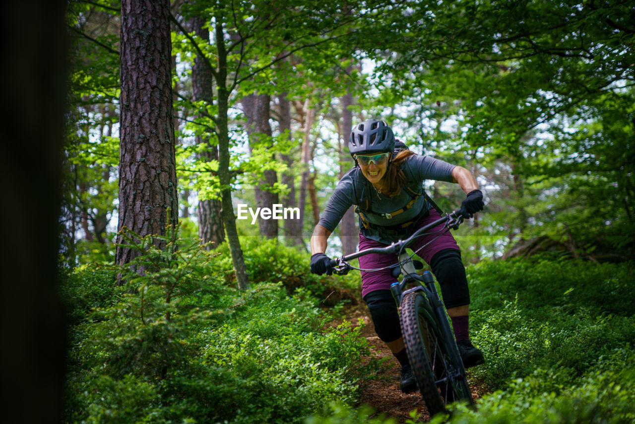 Woman riding mountain bike on footpath amidst trees in forest, austria