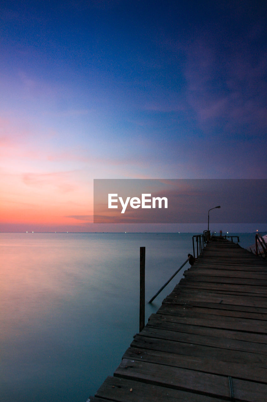 Pier over sea against sky during sunset