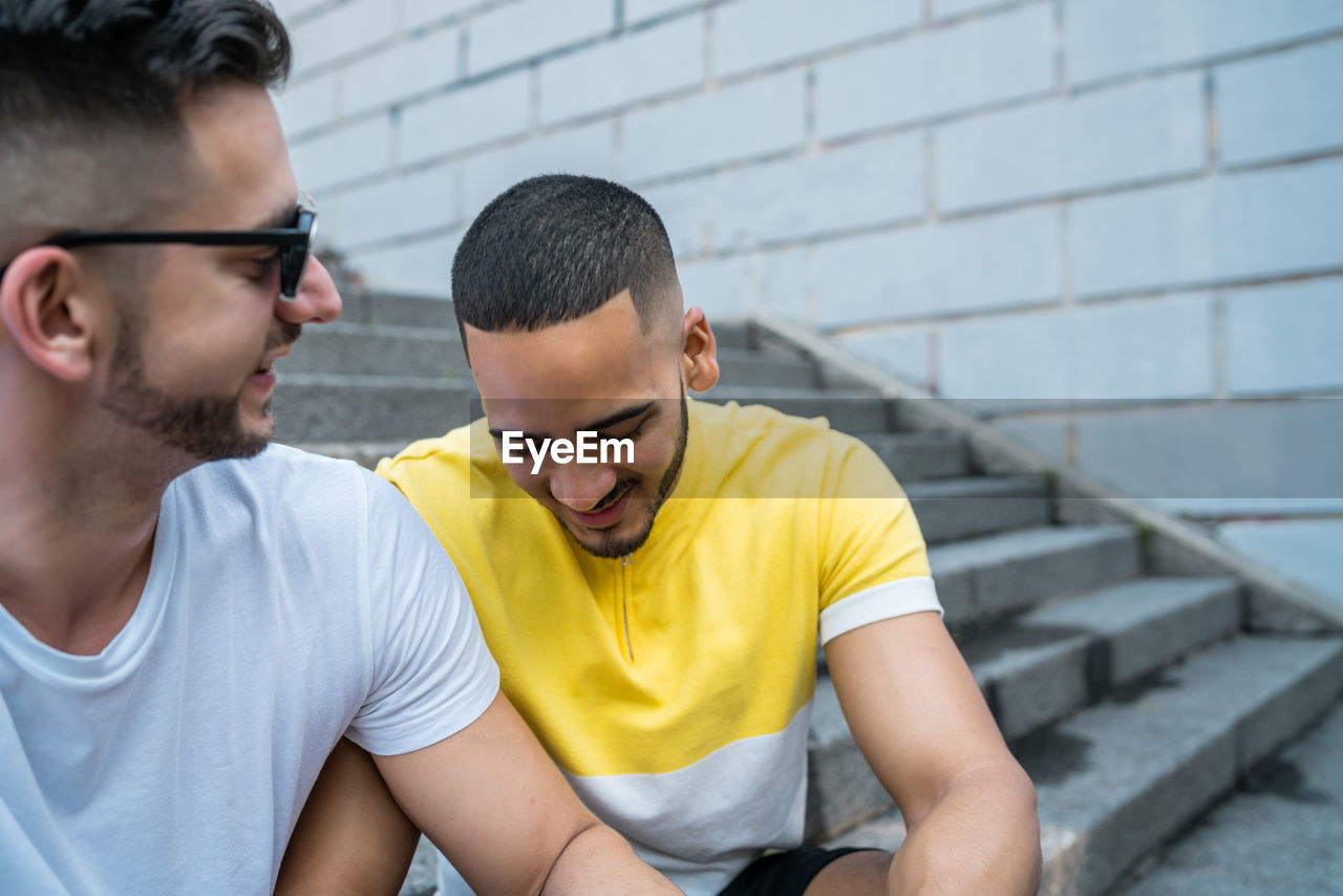 Gay couple sitting on staircase in city