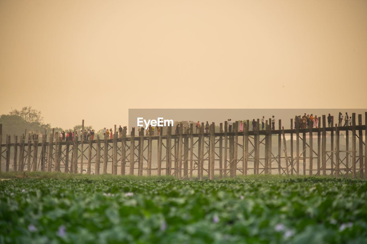 Fence on field against clear sky during sunset