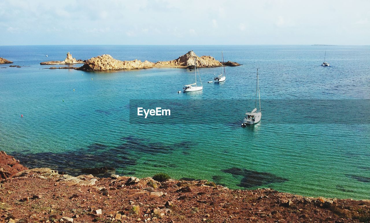 HIGH ANGLE VIEW OF ROCKS IN SEA AGAINST SKY