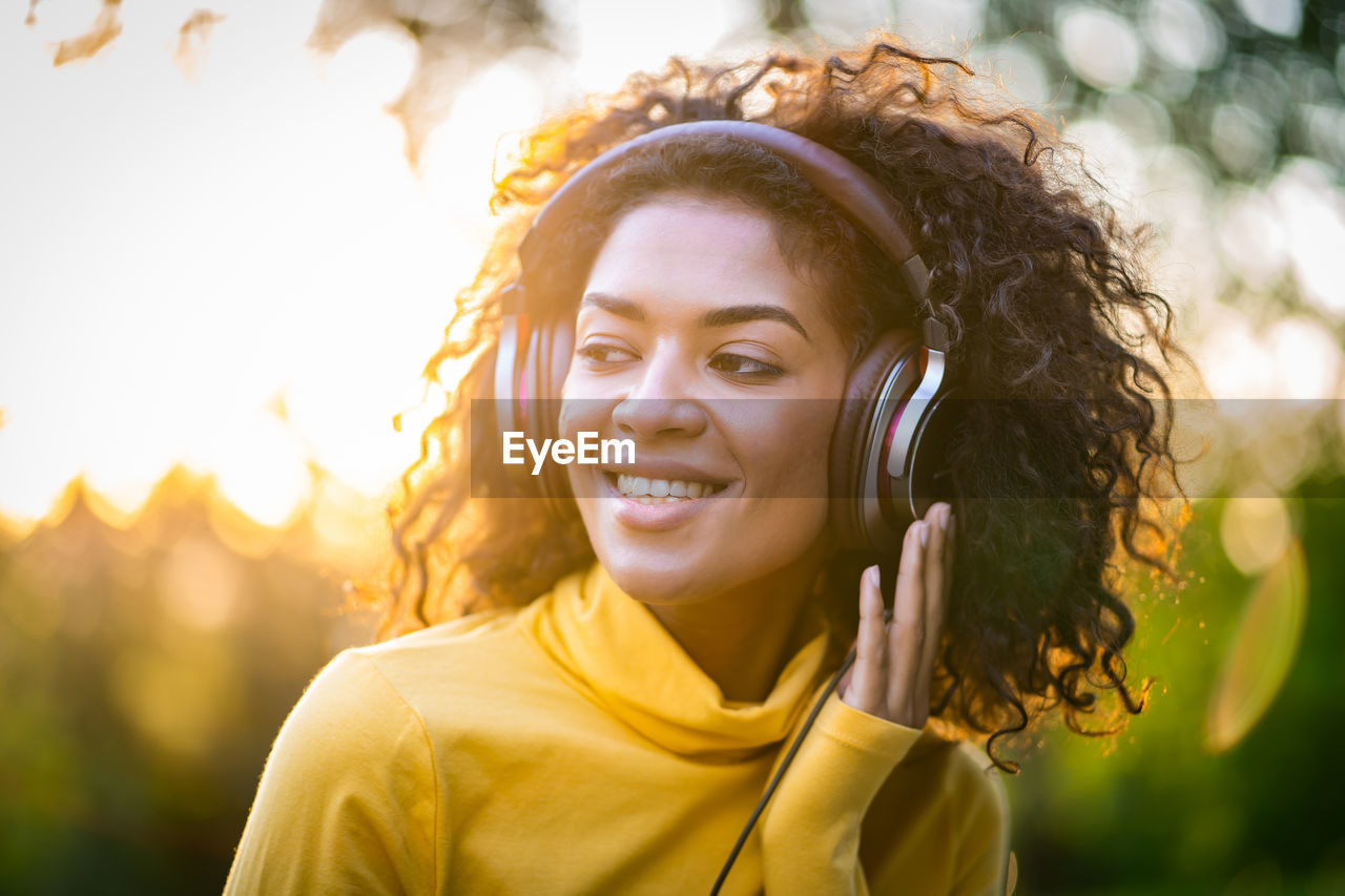 Close-up of beautiful woman wearing headphones standing outdoors