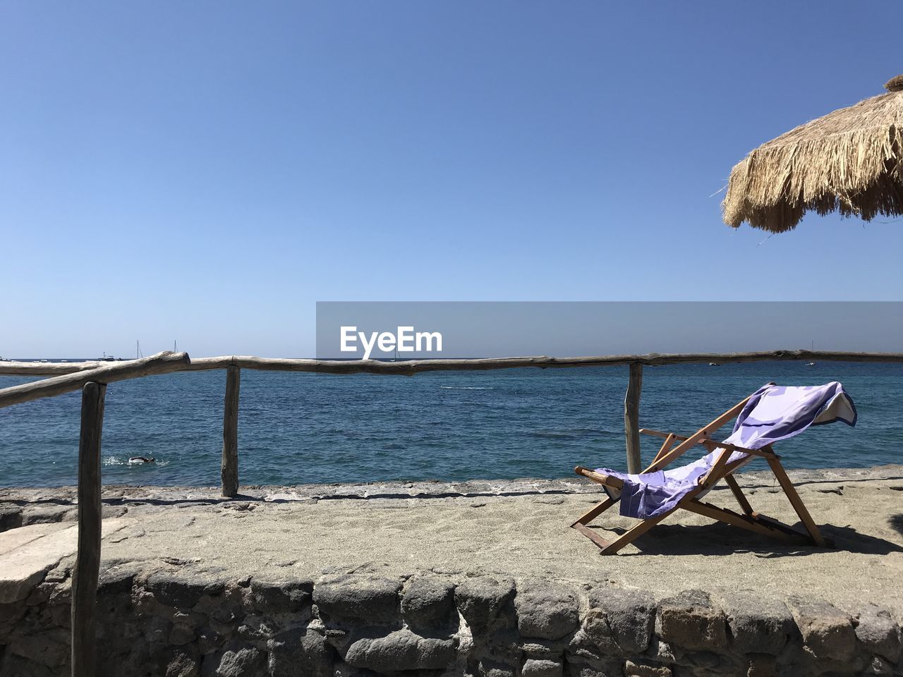 DECK CHAIRS ON SHORE AGAINST CLEAR SKY