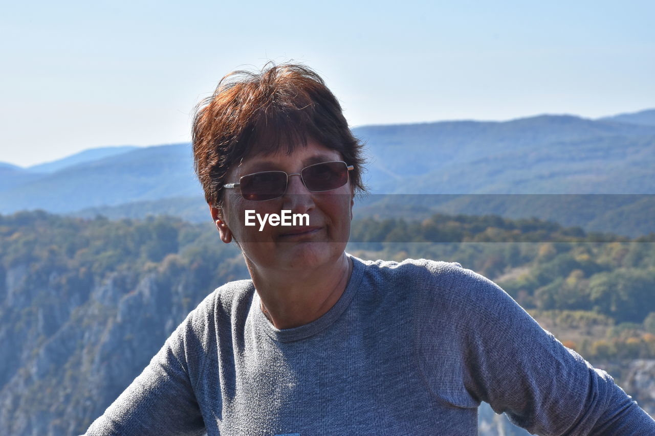 Woman wearing sunglasses against mountains