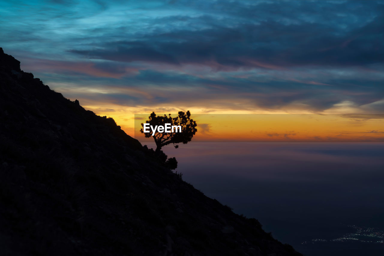 Scenic view of silhouette mountain against orange sky