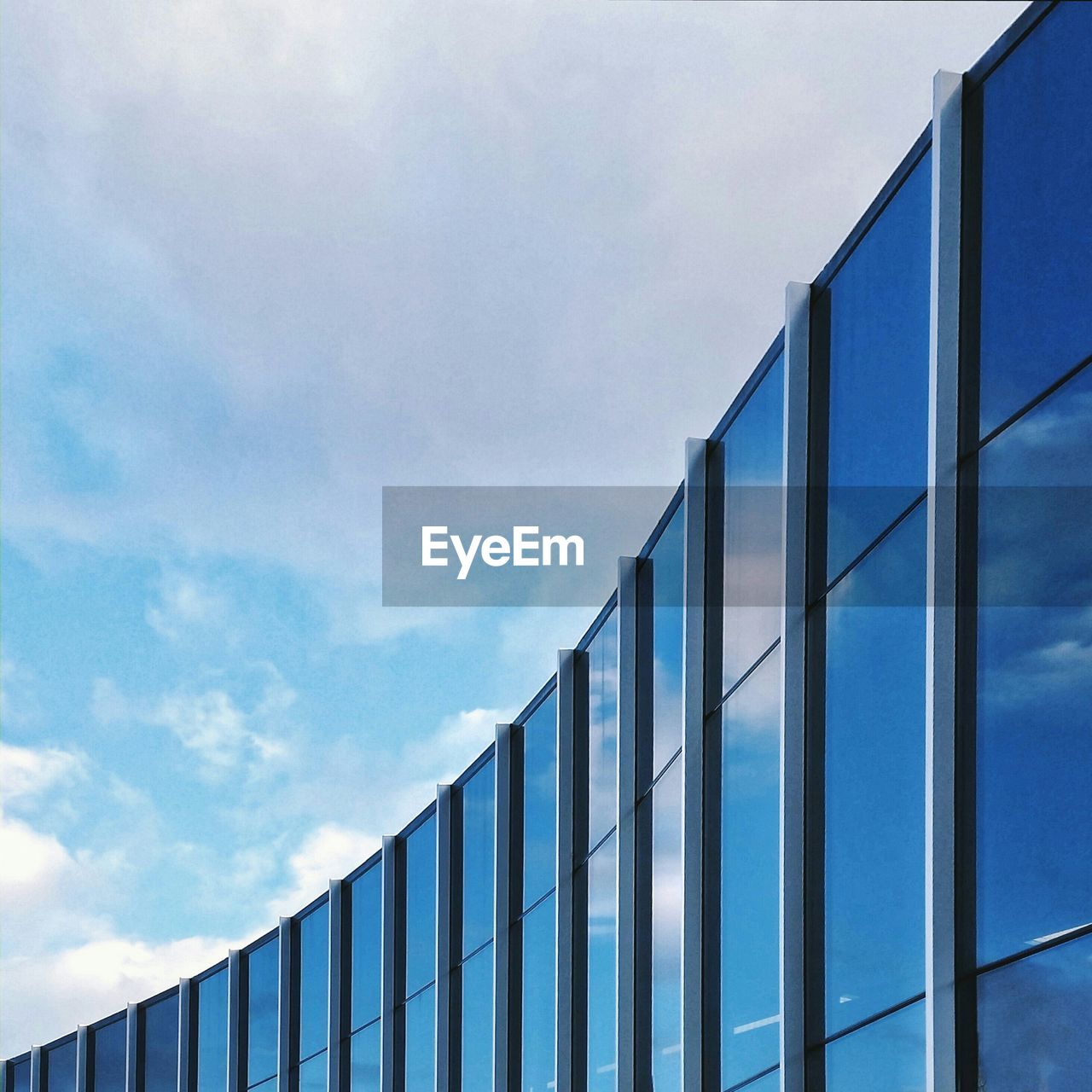 Low angle view of modern office building against cloudy sky