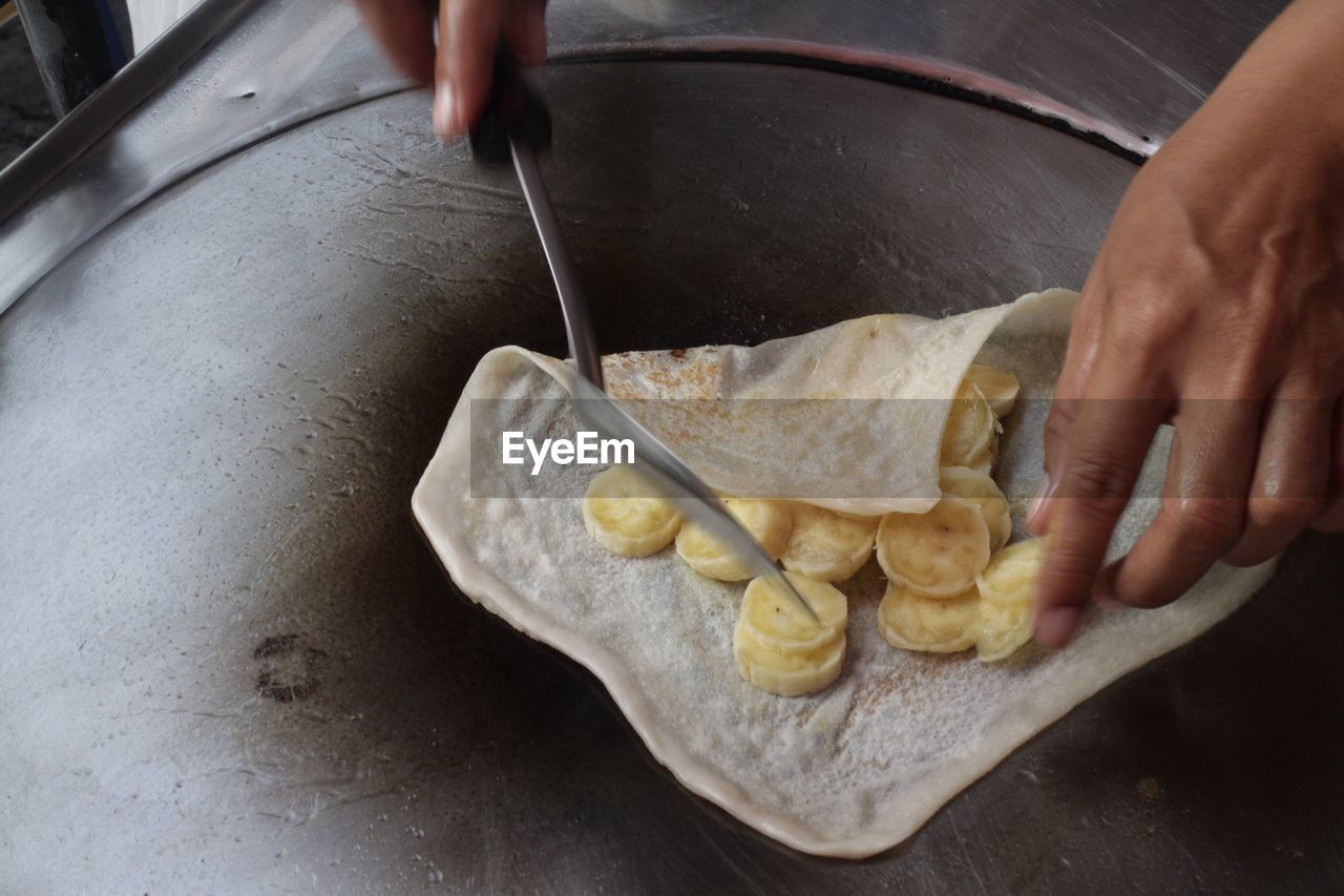 Close-up of person preparing banana crepe