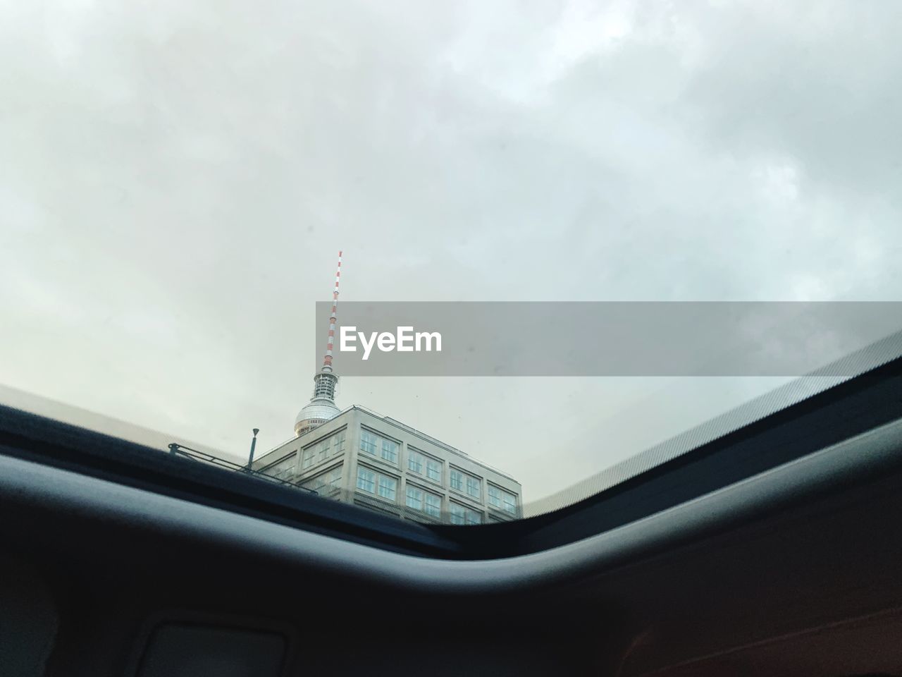 Low angle view of building seen through car against sky