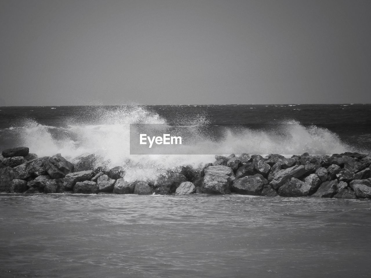 Water splashing on rocks against sky