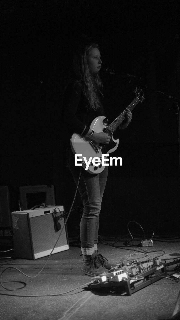 FULL LENGTH OF YOUNG MAN PLAYING GUITAR