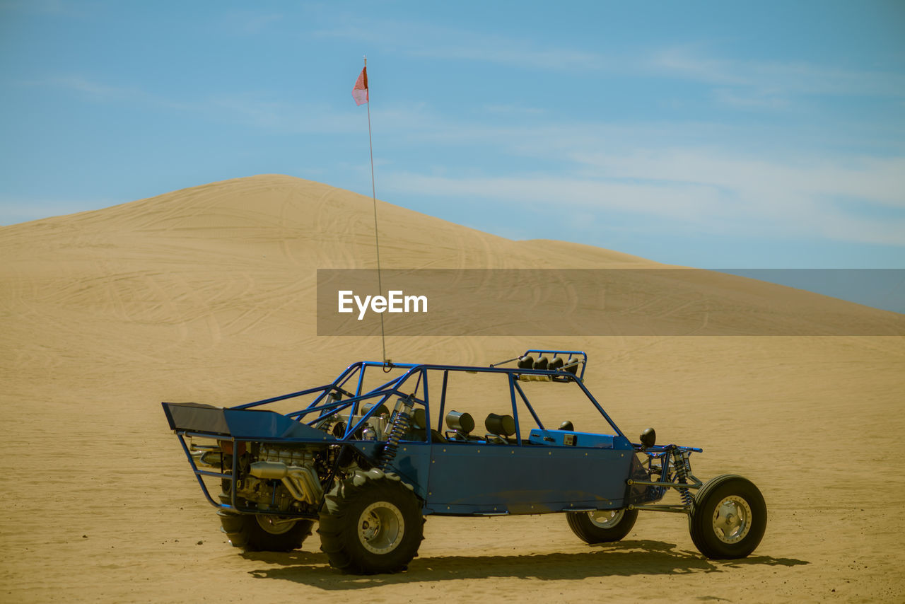 Off-road vehicle in desert against sky