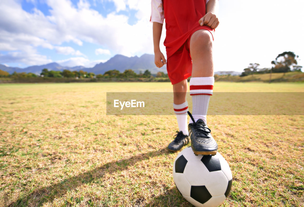 low section of man playing soccer at park