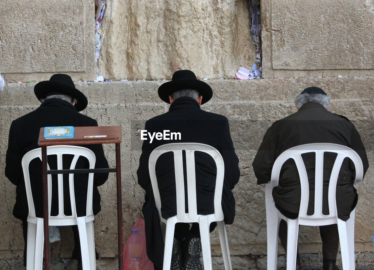 Rabbis sitting on chair in of front wailing wall