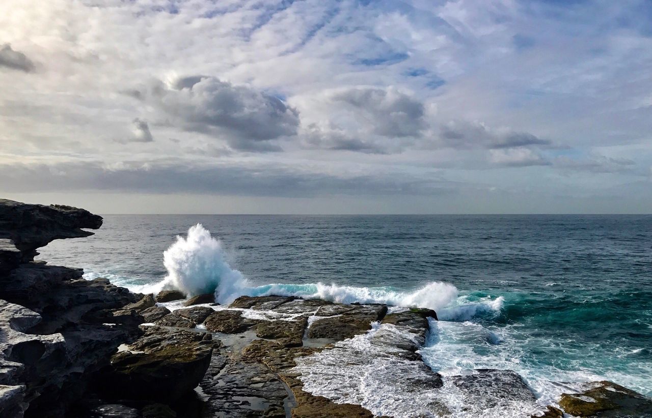 WAVES SPLASHING IN SEA AGAINST SKY