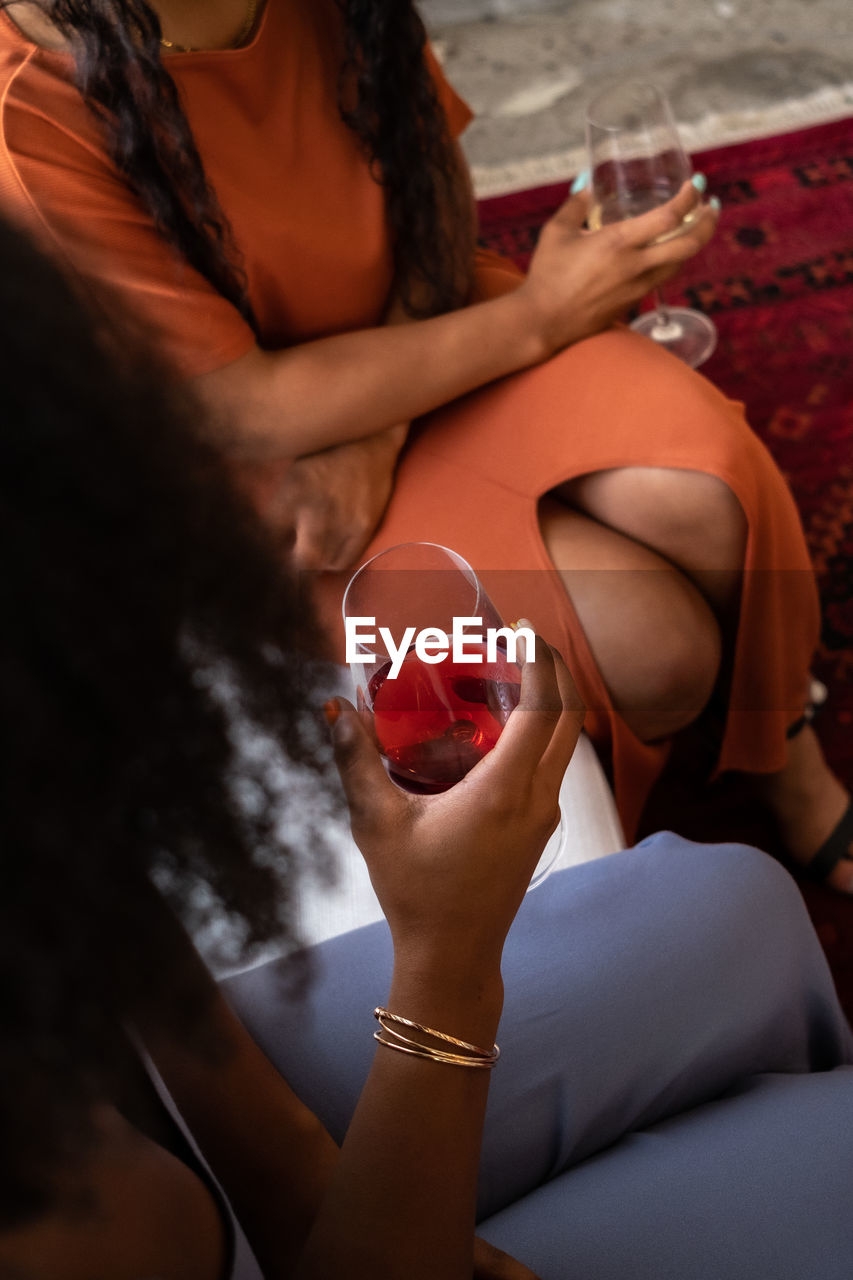 Two women seated and talking with wine glasses in hand 