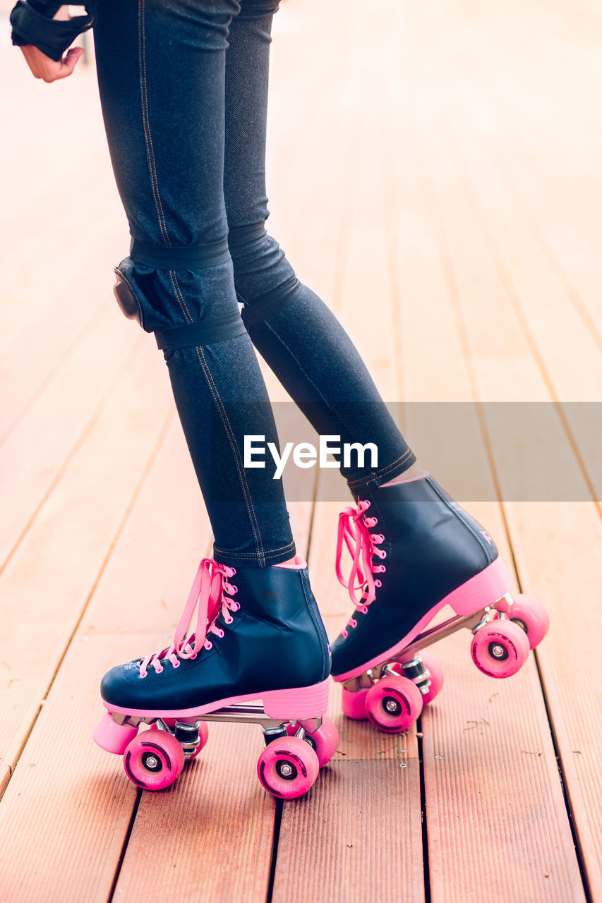 Low section of teenage girl roller skating on boardwalk