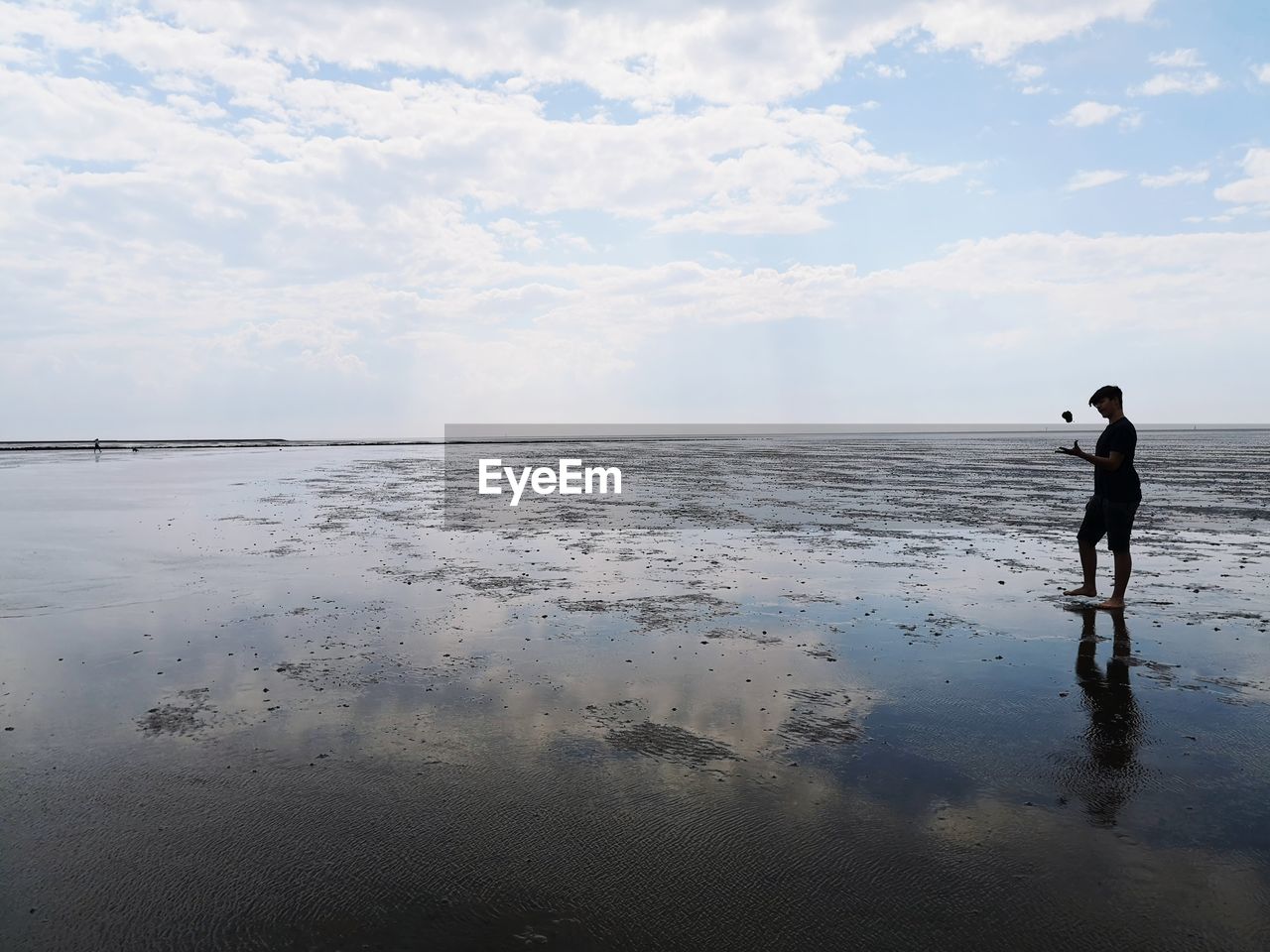 MAN STANDING AT BEACH AGAINST SKY