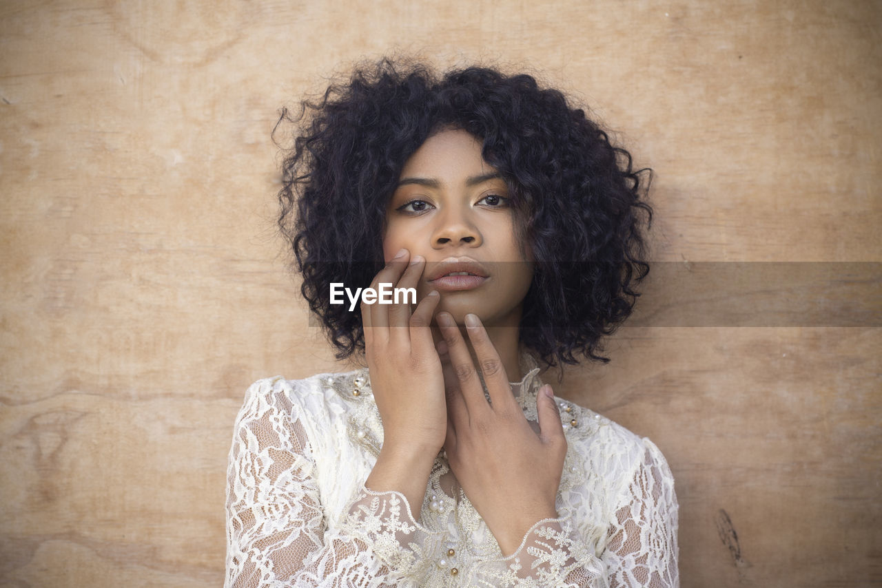 Portrait of young woman looking away against wall