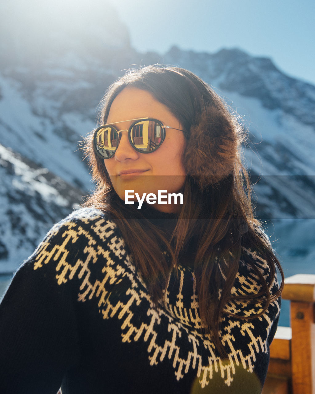 A woman warms up in the sunshine by the mountains in chile.